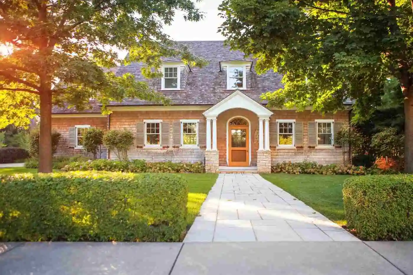 Two-story brick house with a front walk and mature trees
