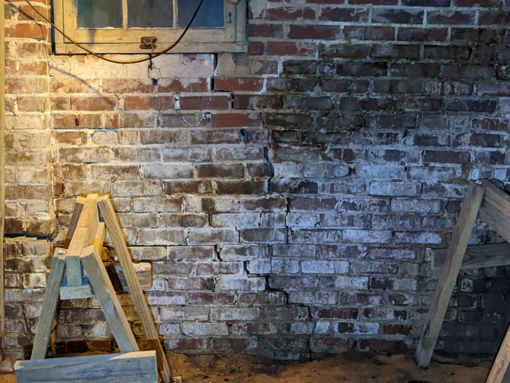 Cracked brick foundation wall inside a crawlspace