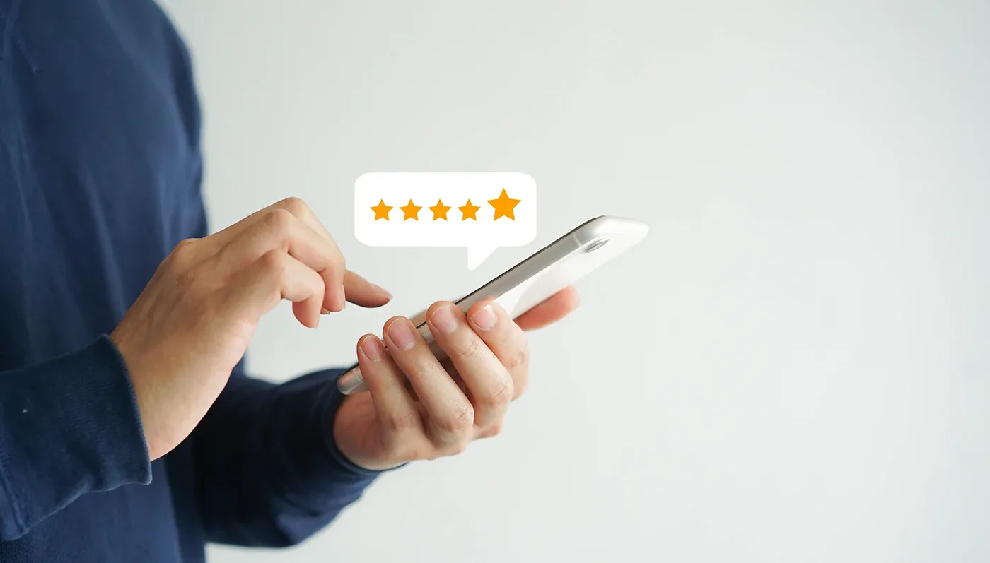 Hand tapping a five star review on a smartphone