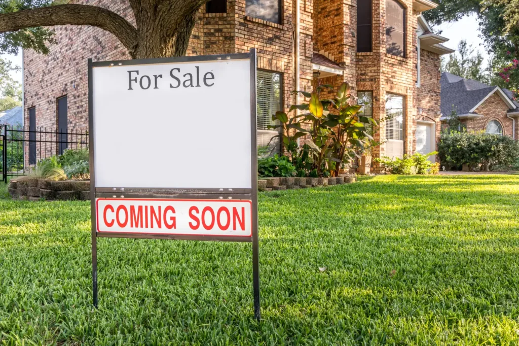 Brick two-story house with a For Sale sign and a Coming Soon rider in the front yard